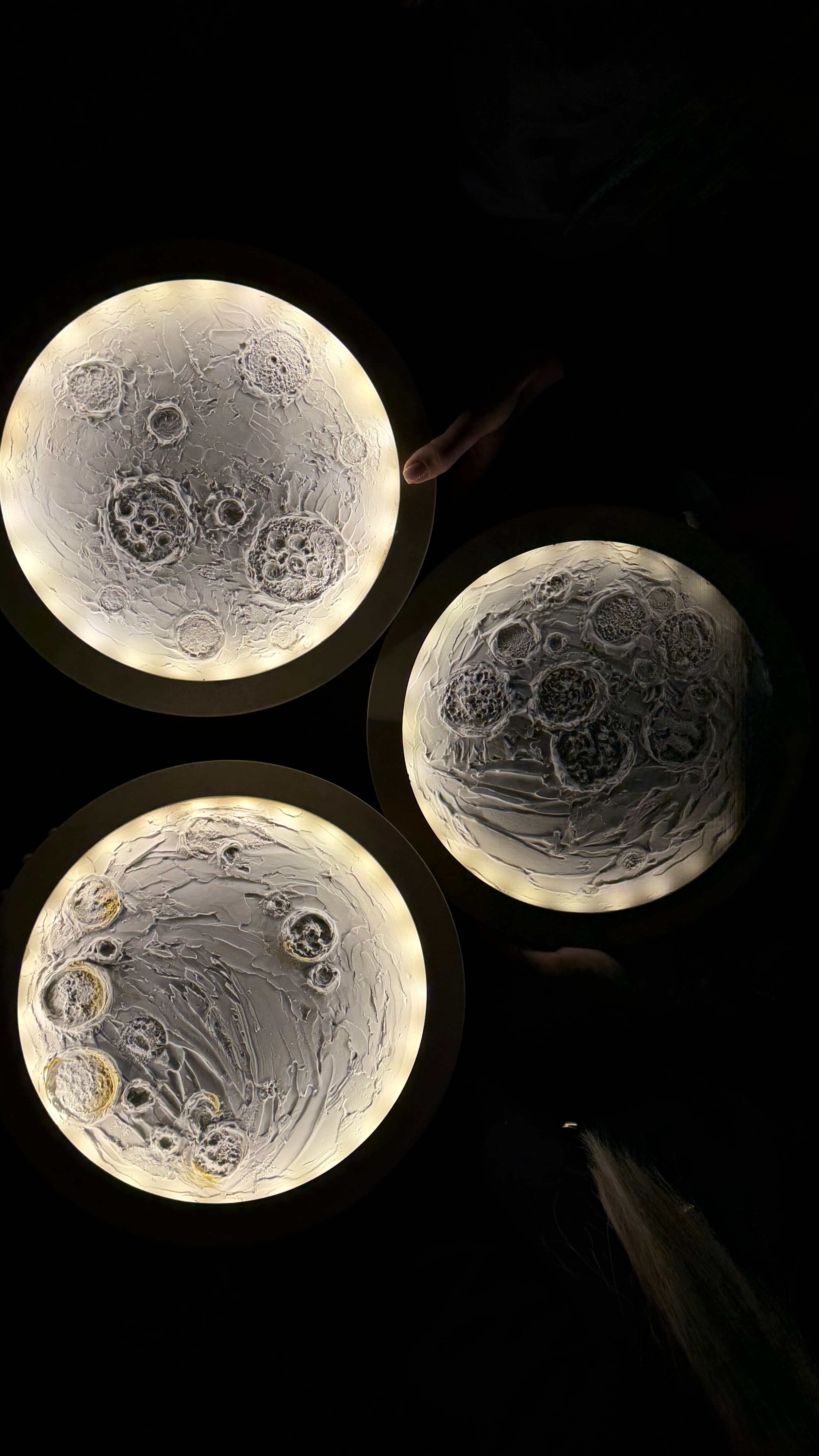 Three finished glowing moon artworks illuminated in the dark
