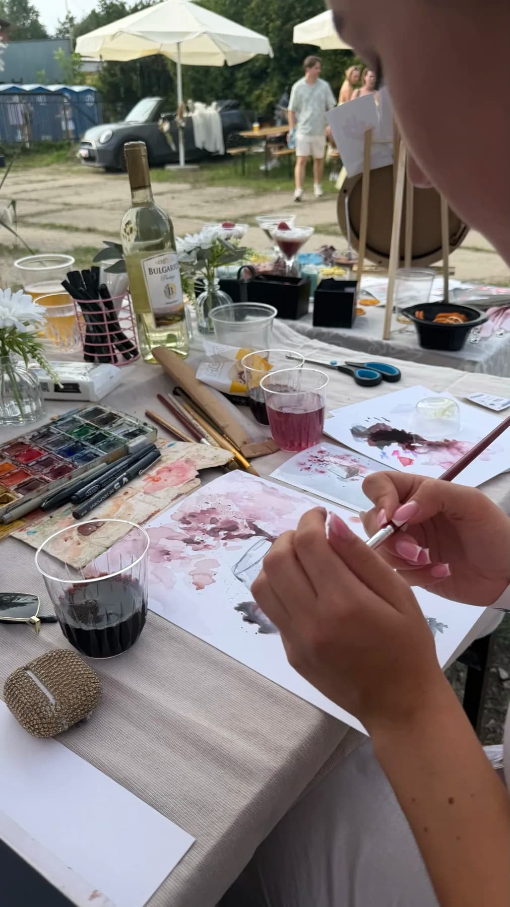 Guest painting with wine at a prepared workshop table